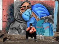 A Palestinian man sits past a mural, showing doctors mask-clad due to the COVID-19 coronavirus pandemic in the Nusseirat refugee camp in the central Gaza Strip on November 16, 2020. Photo by Ashraf Amra